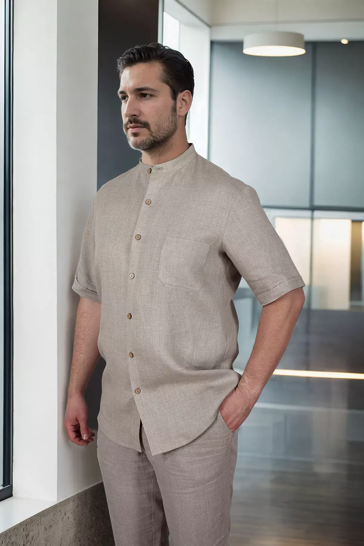 Mężczyzna stoi w półprofilu. Widać bok koszuli i swobodny krój rękawa. Koszula luźno układa się na sylwetce, nie krępując ruchów. Idealna propozycja na ciepłe dni.