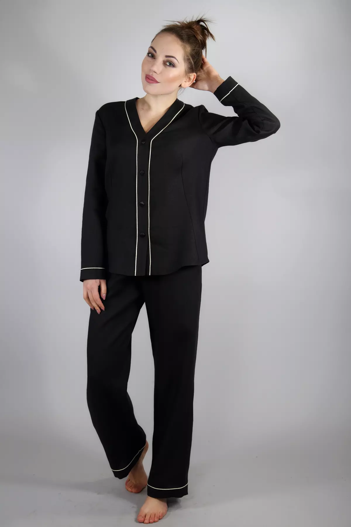 Modelka stoi boso, prezentując wariant z długimi spodniami. Luźne, czarne spodnie lniane i koszula z długim rękawem tworzą spójny, elegancki komplet homewear. Jasna wypustka przy kostkach dodaje lekkości.