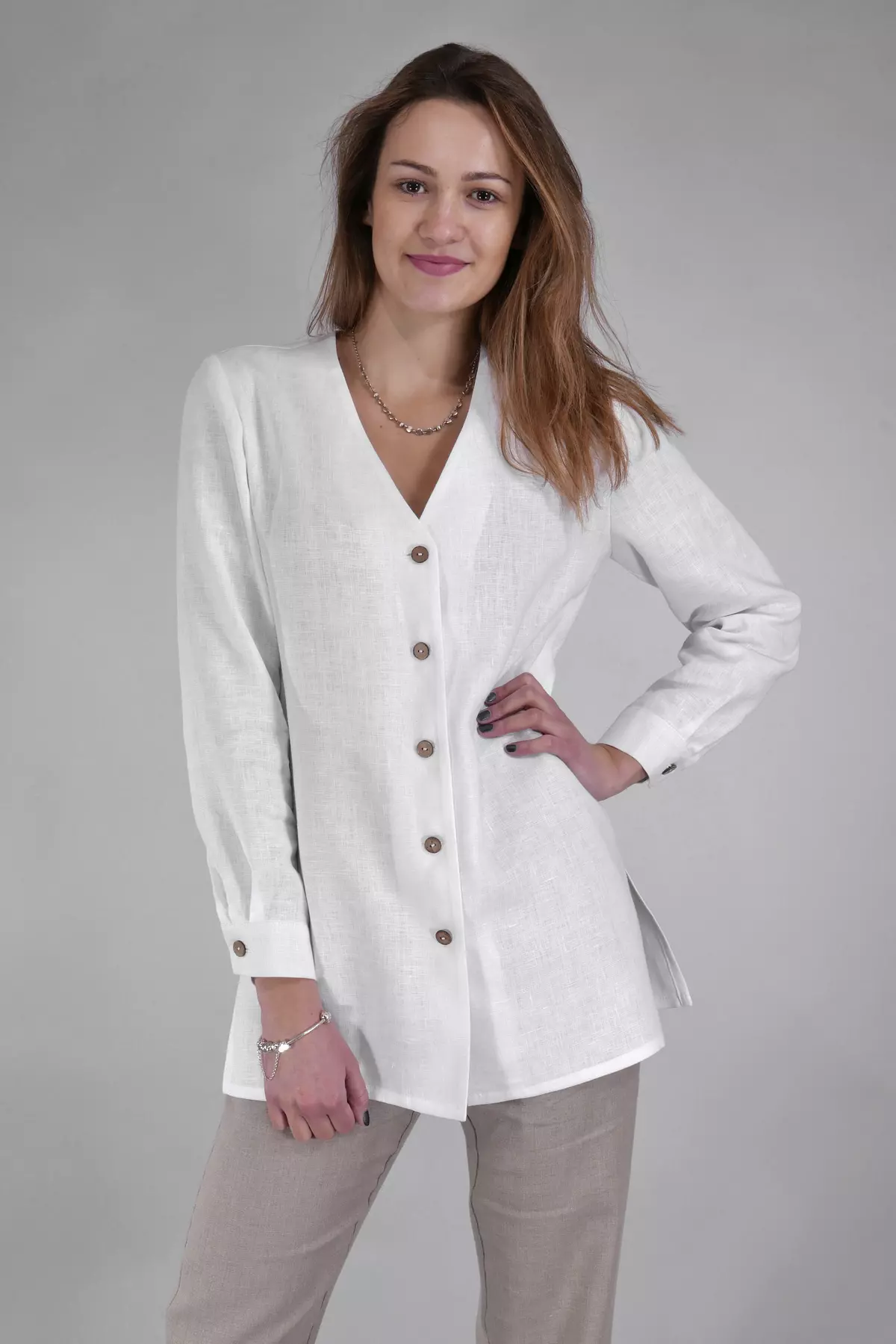 Modelka stoi prosto, opierając jedną rękę na biodrze. Bluzka jest zapięta na wszystkie guziki. Jej dłuższy krój sprawia, że świetnie wygląda noszona na wierzchu spodni. Idealna propozycja casualowa i biurowa.