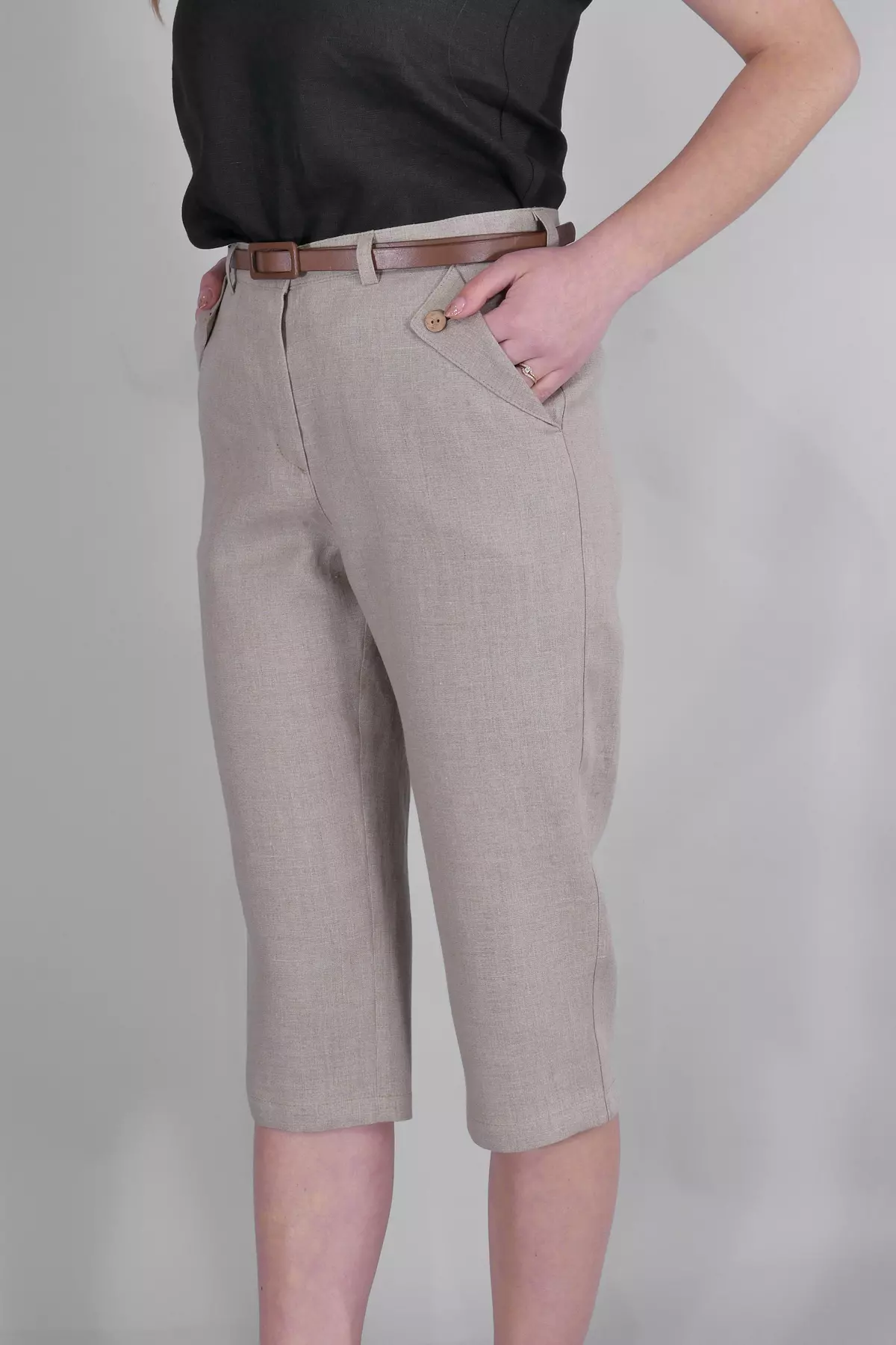 Modelka stoi bokiem, wkładając rękę do kieszeni. Ujęcie pokazuje, jak naturalny len układa się na biodrach i udach. Spodnie są lekko dopasowane, ale nie obcisłe.