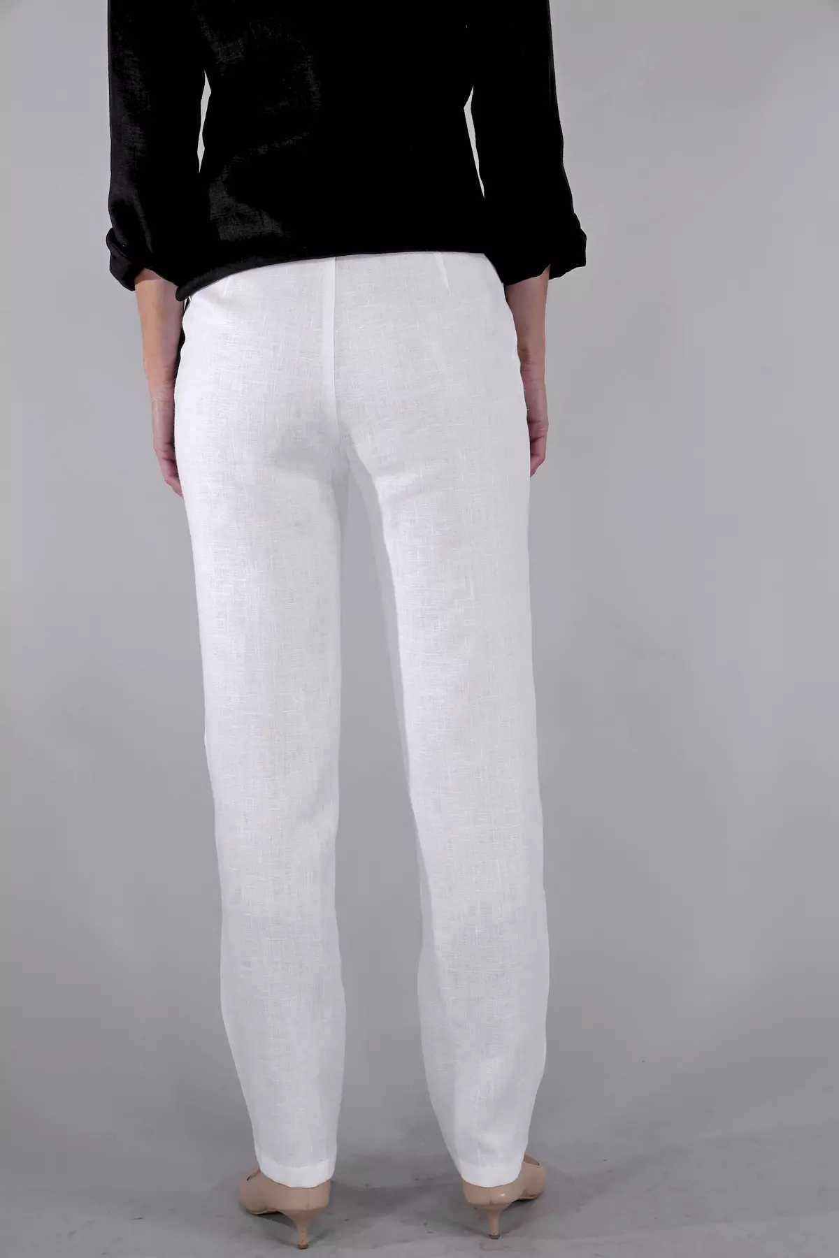 Zbliżenie na tył spodni i pośladki. Widać, że spodnie nie posiadają kieszeni z tyłu, co zapewnia gładką linię sylwetki. Materiał miękko układa się na ciele.