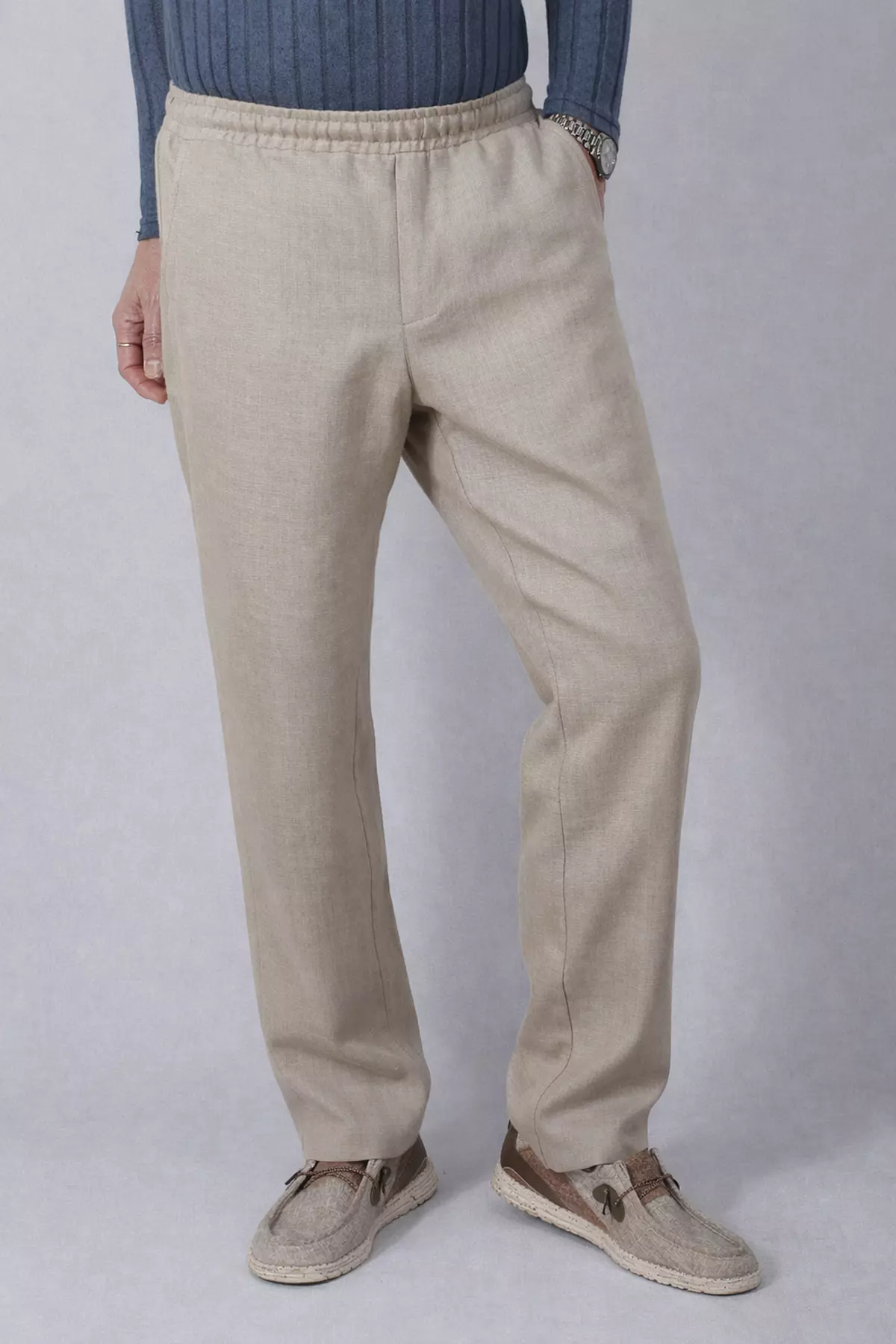 Frontalne ujęcie mężczyzny w spodniach Timo. Model stoi swobodnie, dłonie w kieszeniach. Nogawki spodni są proste, swobodnie opadają na buty. Widać wyraźnie elastyczny pas i brak szlufek, co podkreśla casualowy charakter ubioru.