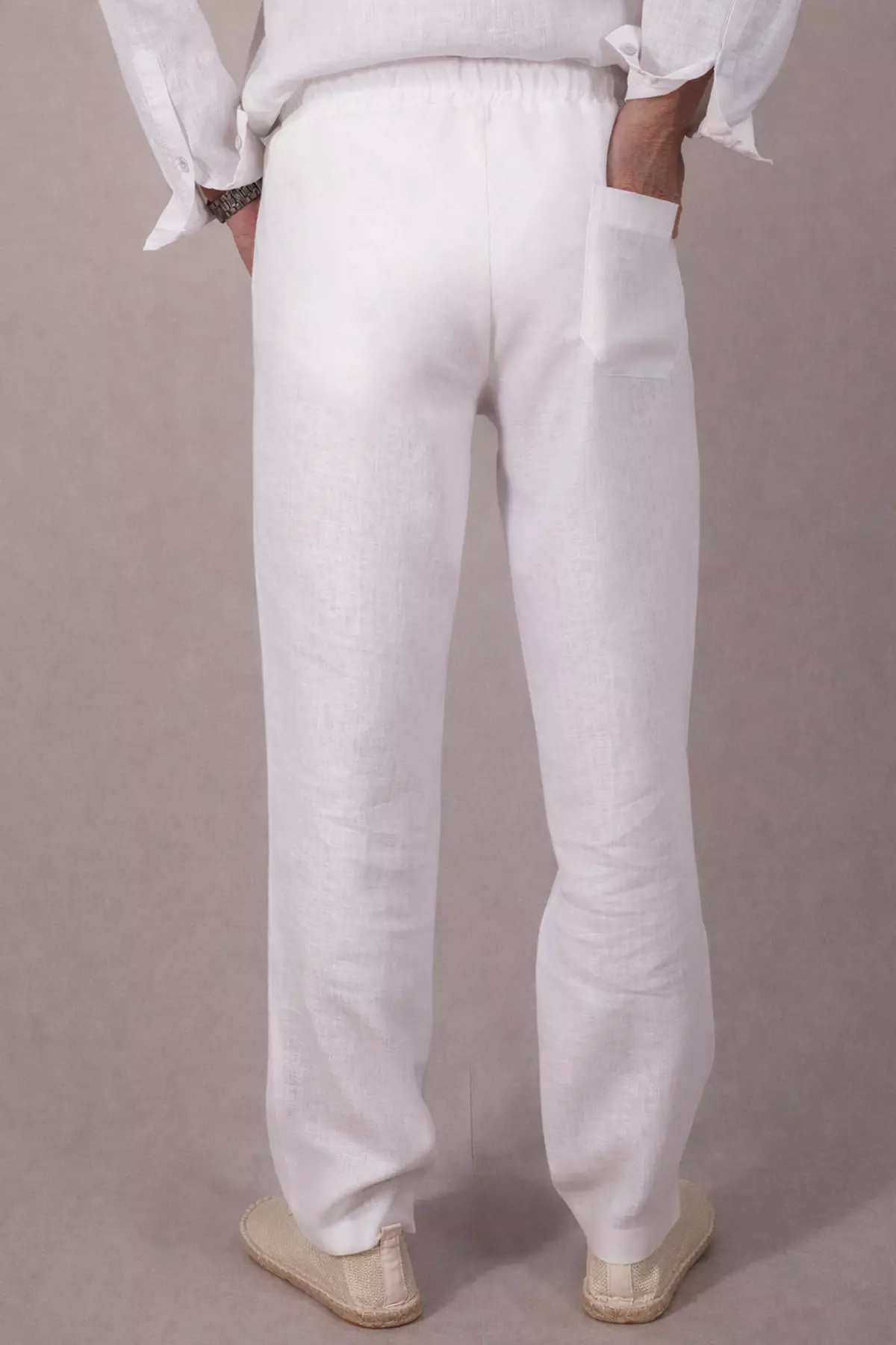 Widok spodni Timo od tyłu. Na prawym pośladku naszyta jest jedna, otwarta kieszeń o prostokątnym kształcie. Biały materiał jest lekko prześwitujący pod światło, co jest naturalną cechą lnu. Nogawki proste, bez ściągaczy.